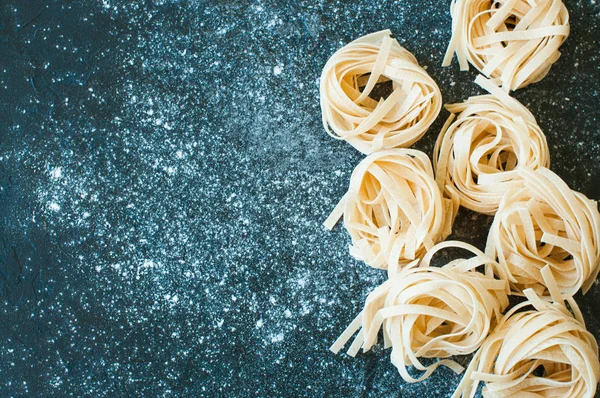 Hausgemachte rohe Pasta auf schwarzem Hintergrund — Stockfoto