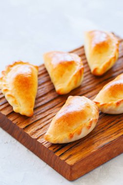Ahşap bir tahta üzerinde ev yapımı patates doldurulmuş empanadas.