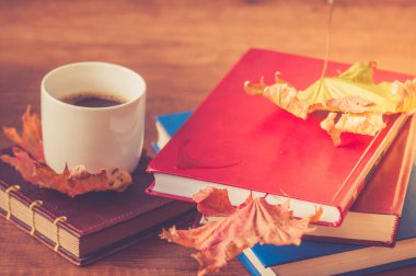 Sonbahar akçaağaç yaprakları ile kahve ve kitap bir fincan.
