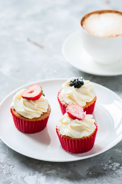 Three vanilla cupcakes with cappuccino on a gray background. — Stock Photo, Image