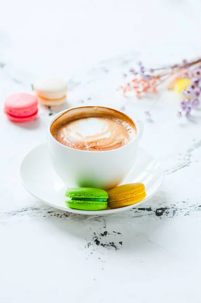 Uma xícara de cappuccino e macarons em um fundo branco . — Fotografia de Stock