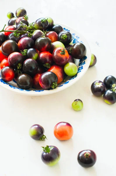 Tomates acastanhados cereja em uma chapa em um fundo branco — Fotografia de Stock