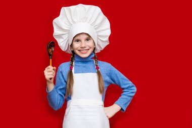 Mutlu küçük kız Şef üniformalı izole kırmızı kaşık tutan. Çocuk Şef. Pişirme işlemi kavramı 
