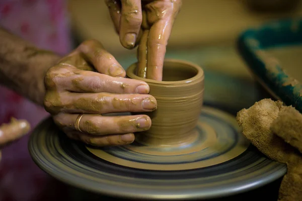 Sculpts in clay pot closeup. Modeling clay close-up. Caucasian man making vessel daytime of white clay in fast moving circle. Art, creativity. Ukraine, cultural traditions. Hobbies