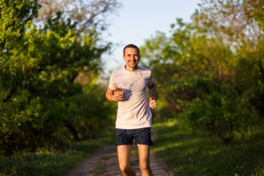 Günbatımı ve dinle müzik Park koşan atletik genç adam. Sağlıklı yaşam tarzı