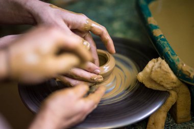 Clay, seçici odak vazo yapma önlük potter yakın çekim elleri. Birlikte zorlaştırıyor. Çanak çömlek çarkı seramik potu kazanmak için öğretim Potter üstten görünüm