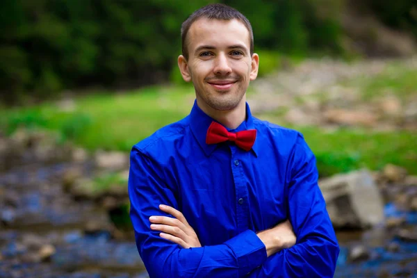 Yakışıklı orman Nehri yakınında mavi gömlek gülümseyen genç portresi. Duygular kavramı