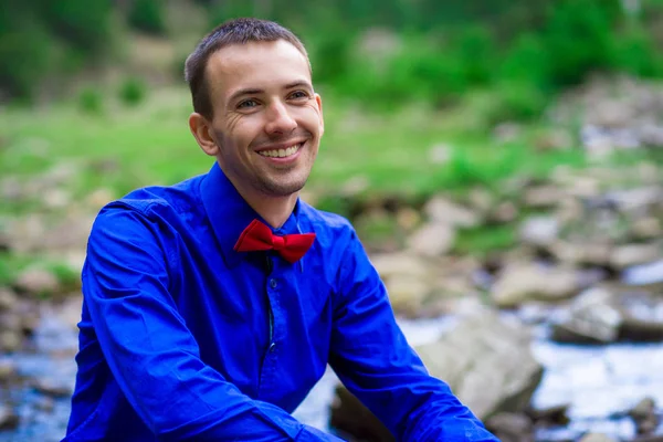 Yakışıklı orman Nehri yakınında mavi gömlek gülümseyen genç portresi. Duygular kavramı