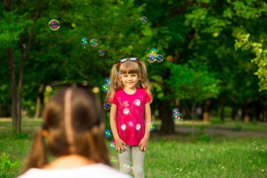 Genç Anne ve küçük kızı sabun köpüğü ile parkta oynarken. Aile, ebeveynlik, çocukluk seviyorum