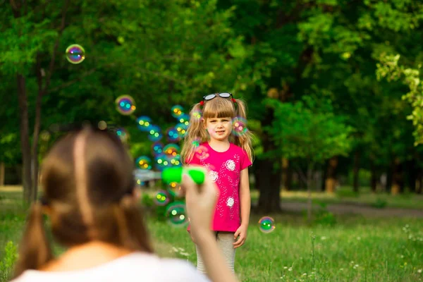 Genç Anne ve küçük kızı sabun köpüğü ile parkta oynarken. Aile, ebeveynlik, çocukluk seviyorum