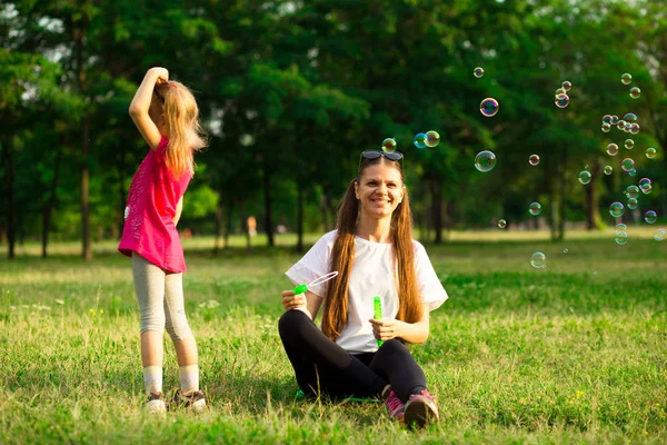Genç Anne ve küçük kızı sabun köpüğü ile parkta oynarken. Aile, ebeveynlik, çocukluk seviyorum