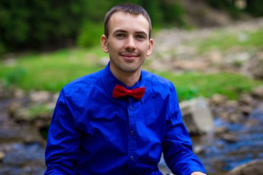 Yakışıklı orman Nehri yakınında mavi gömlek gülümseyen genç portresi. Duygular kavramı