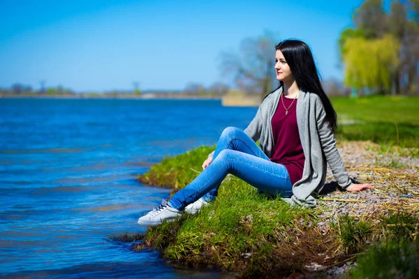 Mooie Jonge Vrouw Spijkerbroek Zit Bank Van Rivier Zonnige Dag — Stockfoto