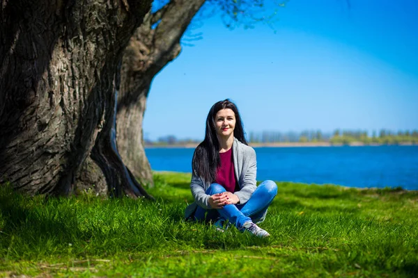 Mooie Jonge Vrouw Jeans Zit Oever Van Rivier Buurt Van — Stockfoto