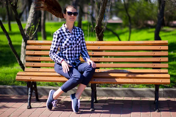 都市公園のベンチの上に座って長い髪を持つ美しい若い女性 — ストック写真