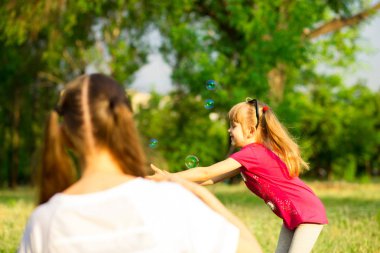 Genç Anne ve küçük kızı sabun köpüğü ile parkta oynarken. Aile, ebeveynlik, çocukluk seviyorum