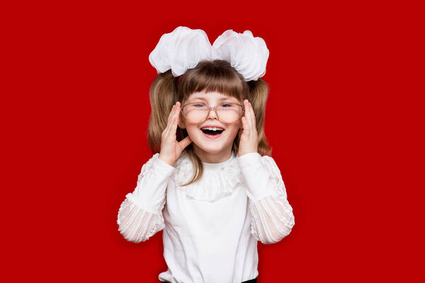 Portrait of cheerful little girl in very big glasses isolated on red. Concept of eyesight or teaching. Education and knowledge concept