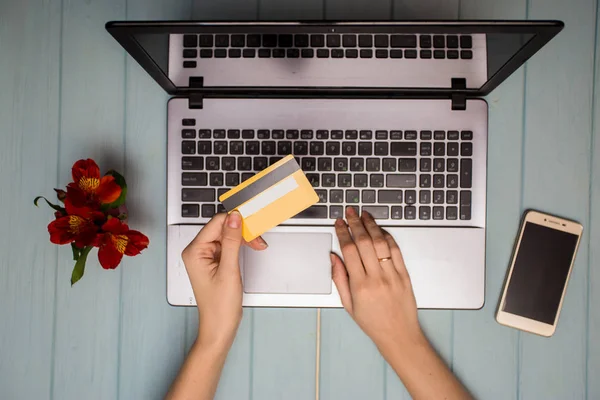 kadın transfer karşılığı banka kredi kartı ile smartphone ve dizüstü evde tutar. yeni teknolojileri kavramı, mal satın online alışveriş. Üstten Görünüm. Düz yatıyordu