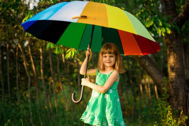 Mutlu çocuk kız yürümek yaz yağmur altında çok renkli şemsiye ile 