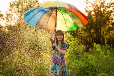 Mutlu çocuk kız yürümek yaz yağmur altında çok renkli şemsiye ile 