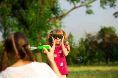Genç Anne ve küçük kızı sabun köpüğü ile parkta oynarken. Aile, ebeveynlik, çocukluk seviyorum