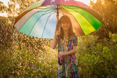 Mutlu çocuk kız yürümek yaz yağmur altında çok renkli şemsiye ile 