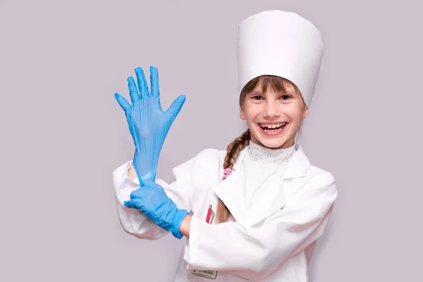 医療制服と青用手袋白で隔離カメラ目線の笑顔の少女 — ストック写真
