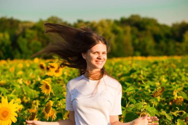 Beyaz saç ayçiçeği alanındaki uçan ile mutlu genç kadın portresi yaz