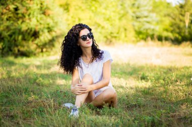 Çok kıvırcık kadınla çimenlerin üzerinde güneşli bir günde poz