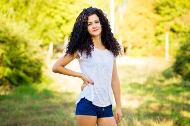 Çok kıvırcık kadınla çimenlerin üzerinde güneşli bir günde poz