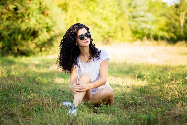 Çok kıvırcık kadınla çimenlerin üzerinde güneşli bir günde poz