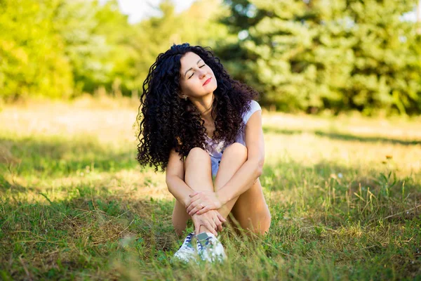 Çok kıvırcık kadınla çimenlerin üzerinde güneşli bir günde poz