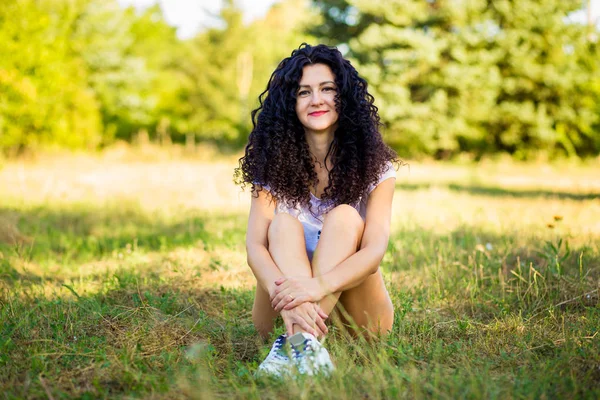 Çok kıvırcık kadınla çimenlerin üzerinde güneşli bir günde poz