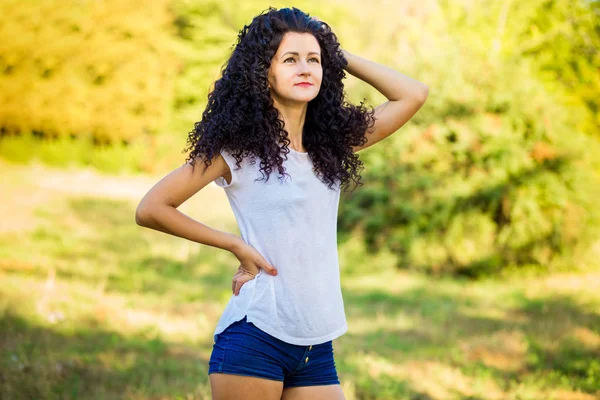 Çok kıvırcık kadınla çimenlerin üzerinde güneşli bir günde poz