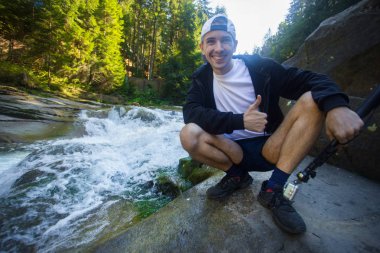 Genç adam yürüyüş ormanın ortasında hızlı Nehri yakınında