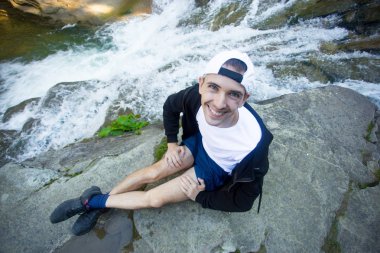 Genç adam yürüyüş ormanın ortasında hızlı Nehri yakınında