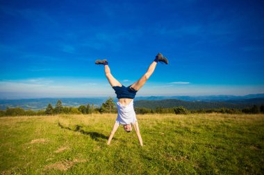Genç mutlu erkek eğleniyor tepenin üstünde, arka planda dağlar