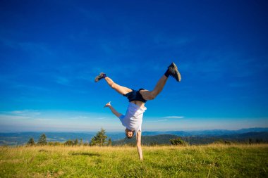 Genç mutlu erkek eğleniyor tepenin üstünde, arka planda dağlar