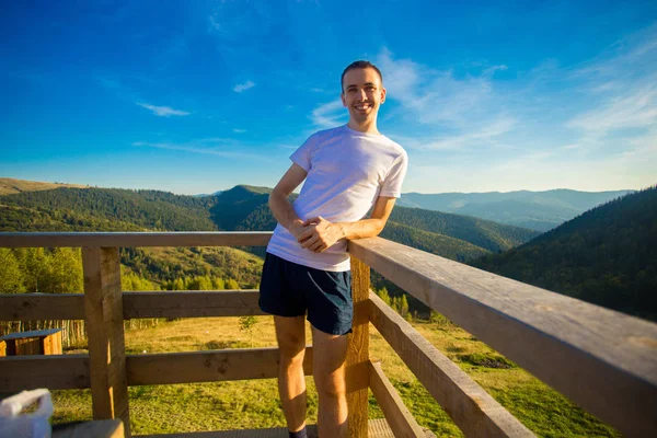Молодой Человек Сидит Заборе Деревянной Террасы Наслаждается Прекрасным Видом Горы — стоковое фото