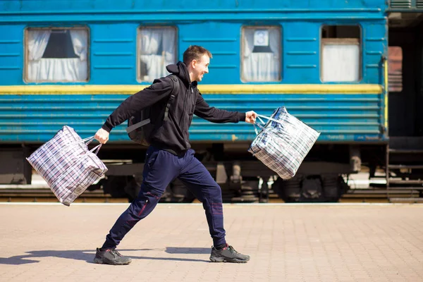 Young man with big bags at railway station. Travel by train
