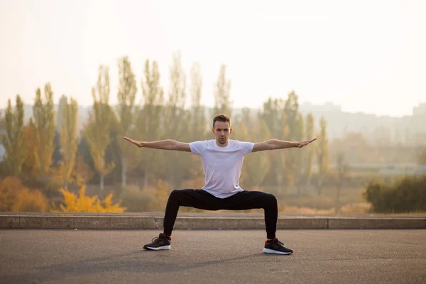 Young male jogger athlete training and doing workout outdoors in city