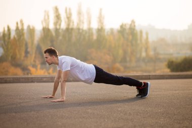 Açık havada yukarı itin yapan genç atletik erkek. Atletik bir adam. Adam doğa sporları yapan. Spor hayatı.