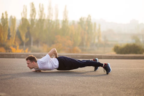 Young athletic man doing push up outdoors. Athletic man. Guy engaged in sports on nature. Sport life.