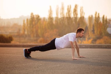 Açık havada yukarı itin yapan genç atletik erkek. Atletik bir adam. Adam doğa sporları yapan. Spor hayatı.