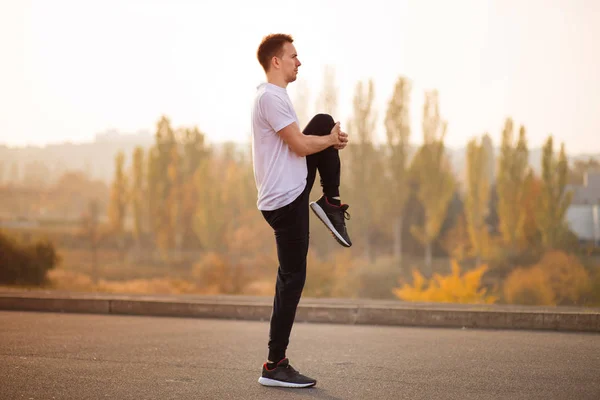 Young male jogger athlete training and doing workout outdoors in city