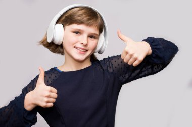 Mutlu gülümseyen çocuk kulaklık müzik dinler beyaz arka plan üzerinde sahiptir.