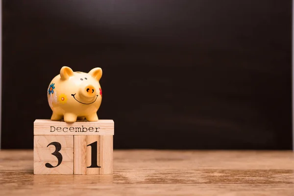 Calendar date for End of Financial Year, 31 december with piggy bank on dark background, with copy space.