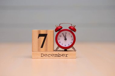7 Aralık ahşap takvim ve mavi arka plan ile kırmızı alarm saati ayarlayın. Gece yarısına 5 dakika gösterilen saat yüzünü