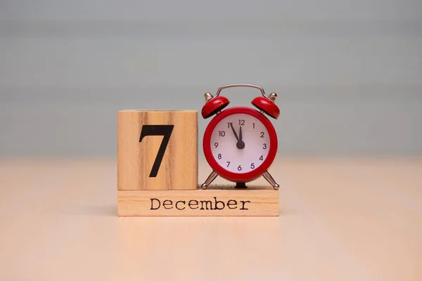 7 Aralık ahşap takvim ve mavi arka plan ile kırmızı alarm saati ayarlayın. Gece yarısına 5 dakika gösterilen saat yüzünü