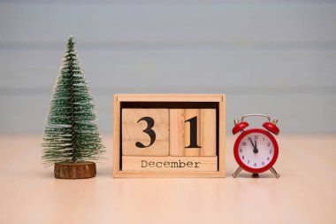 Yeni yıl ağacı ve mavi arka plan üzerinde kırmızı çalar saat ile ahşap takvimde 31 Aralık ayarla. Saati göster gece yarısına 5 dakika